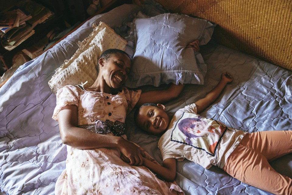 Fara en haar dochter op het bed dat ze samen met Dada Paul delen.