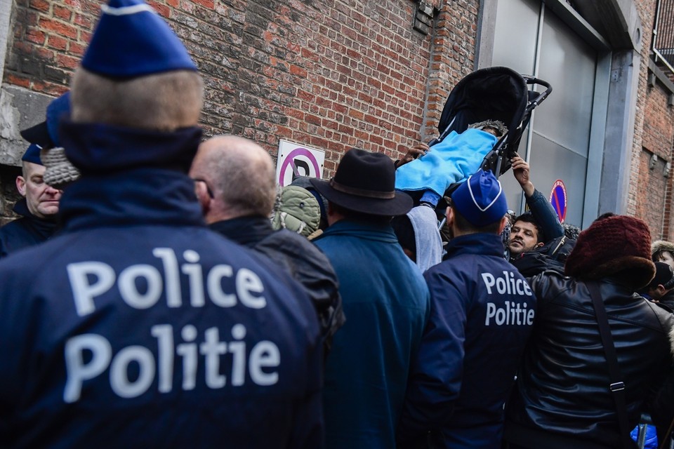 Politie houdt een oogje in het zeil terwijl vluchtelingen aanschuiven om hun asielaanvraag in te dienen. 