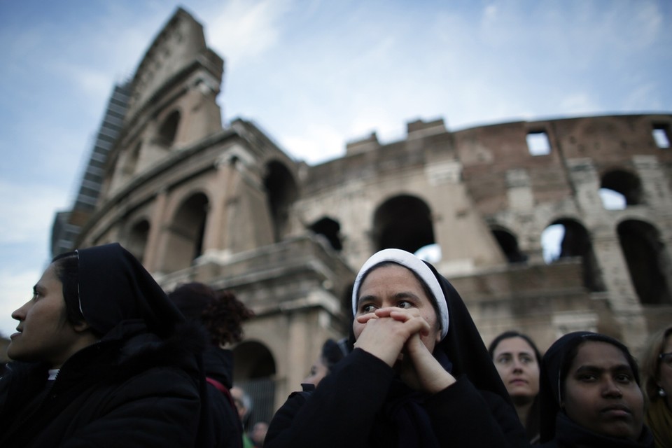 Een non bidt op Goede Vrijdag voor het colosseum in Rome.