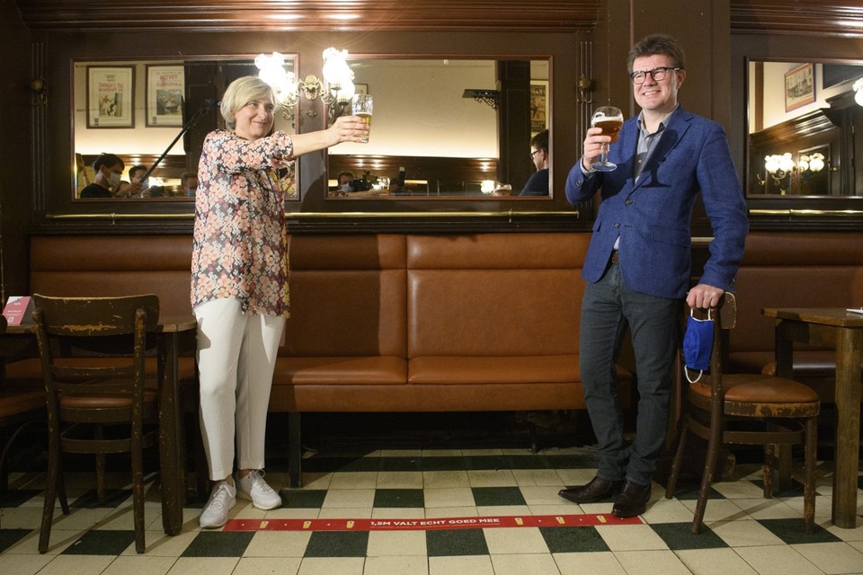 Vlaams minister Hilde Crevits en Brussels minister Sven Gatz drinken op afstand, al vergeten ze wel neer te zitten aan hun tafeltje.