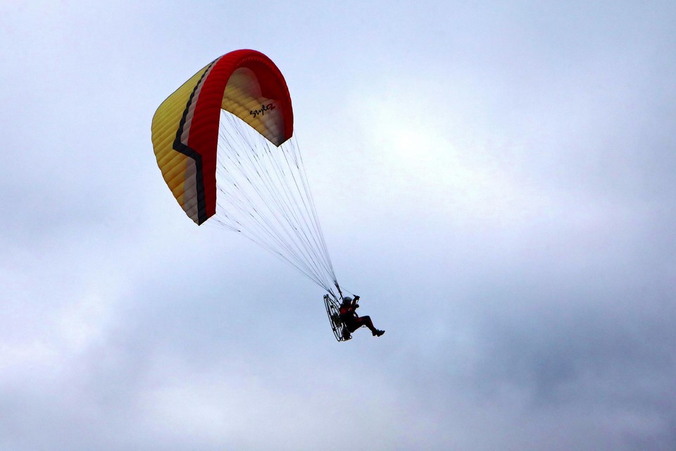 Bij paragliden zweeft iemand rond met een parachute, aangedreven door een motor op de rug.  