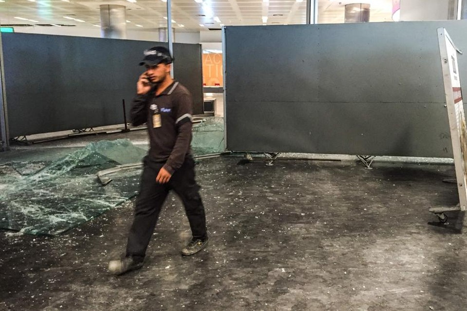 Een werknemer van de luchthaven loopt voorbij glasscherven.