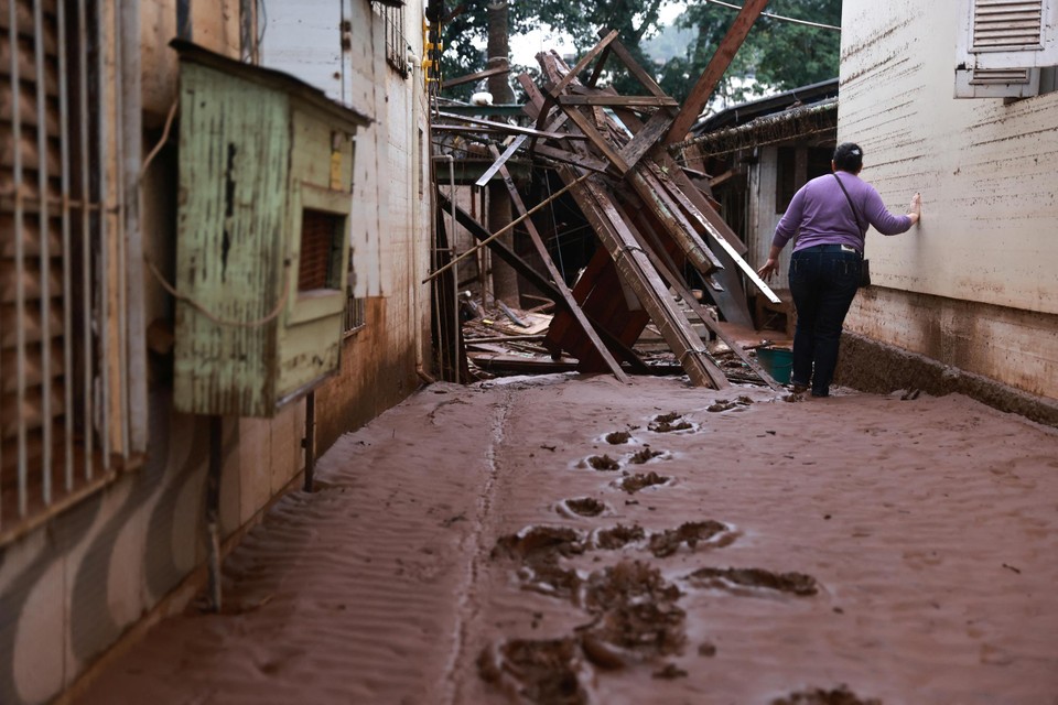 Een vrouw probeert door de modder haar beschadigde woning te bereiken in Encantado.