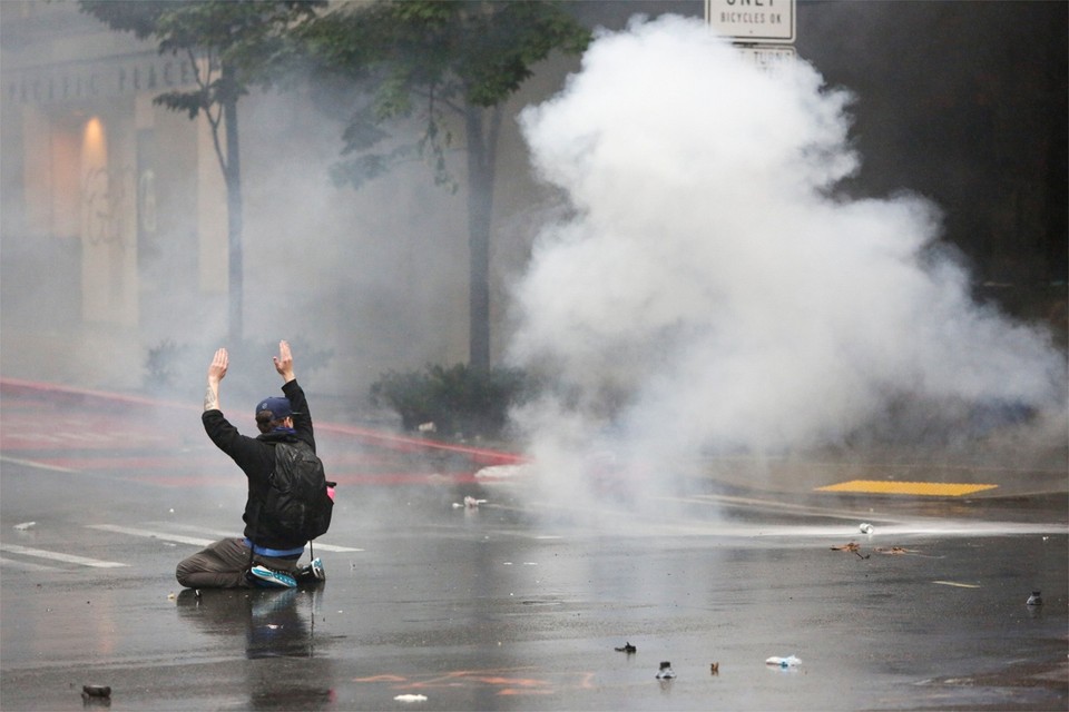 Seattle, Washington. Een betoger knielt en steekt de handen in de lucht tijdens een uit de hand gelopen protest wegens de dood van George Floyd 