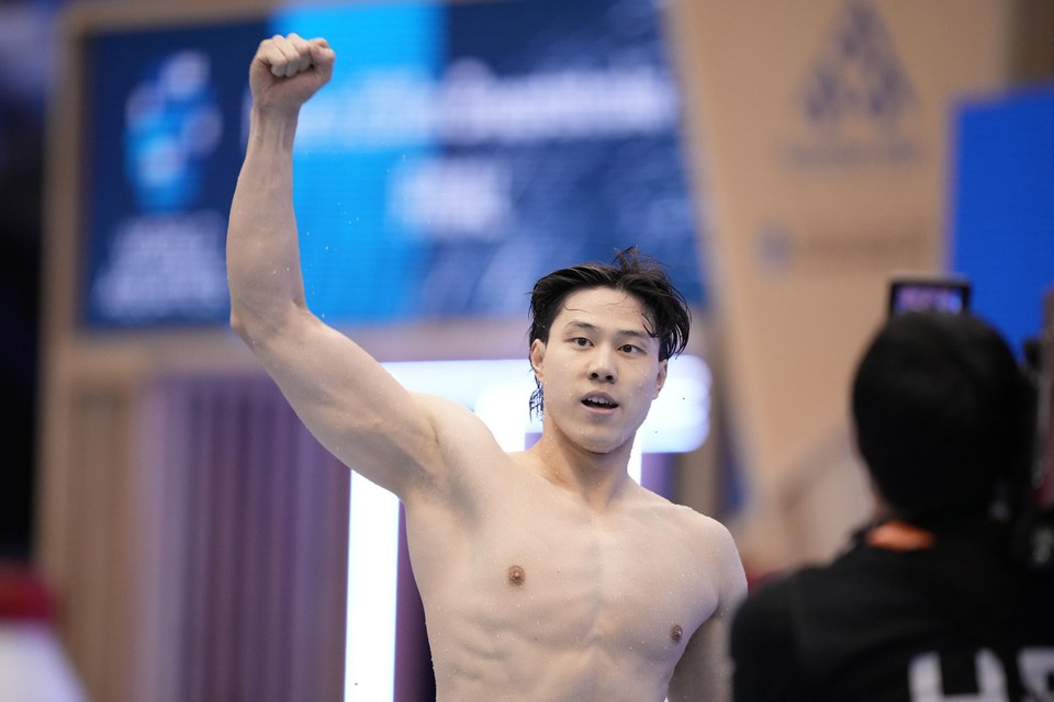 Qin Haiyang viert zijn overwinning op de 200 meter schoolslag op het WK in Japan in 2023.