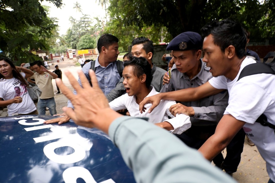 Een journalist protesteert aan de politiewagen die Wa Lone en Kyaw Soe Oo wegvoert 