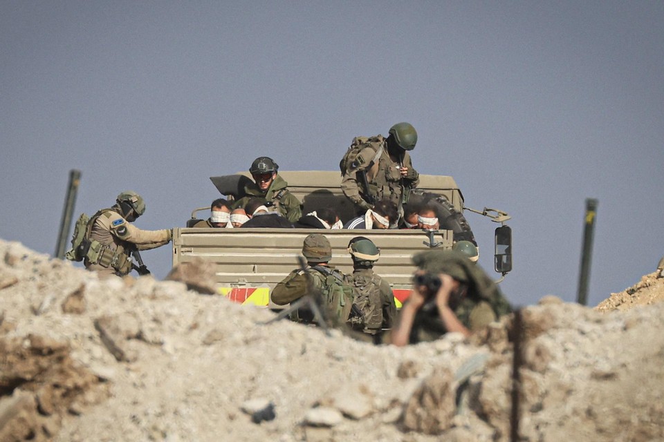 Israëlische soldaten bewaken geblinddoekte Palestijnen in een militaire truck in het zuiden van de Gazastrook.