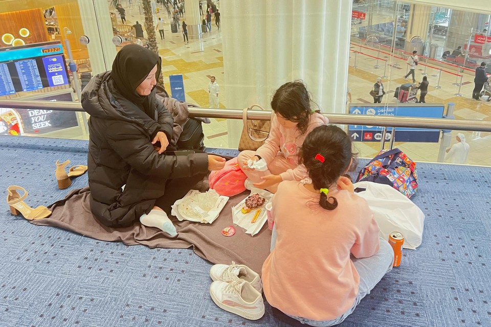 Een vrouw en haar kinderen picknicken in de luchthaven van Dubai.
