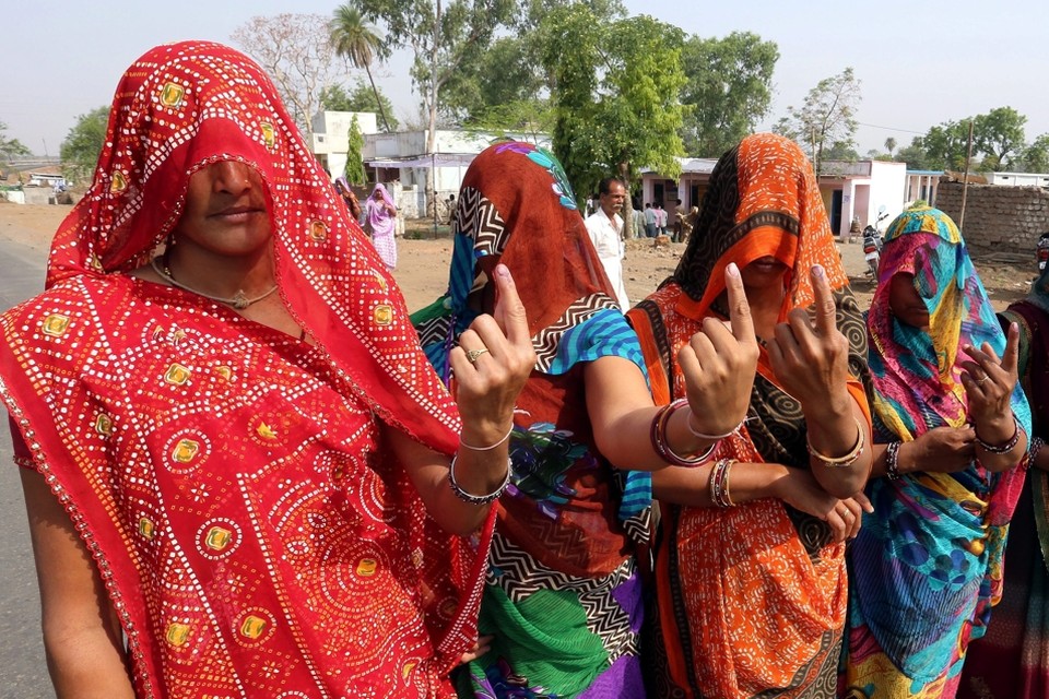 Indiase vrouwen tonen hun vinger met inkt nadat ze gestemd hebben.