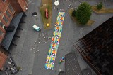 thumbnail: Een picknickdeken van maar liefst 200 vierkante meter, gemaakt van oude vlaggen van de Genkse stadsdiensten, en geproduceerd door Flagbag. 