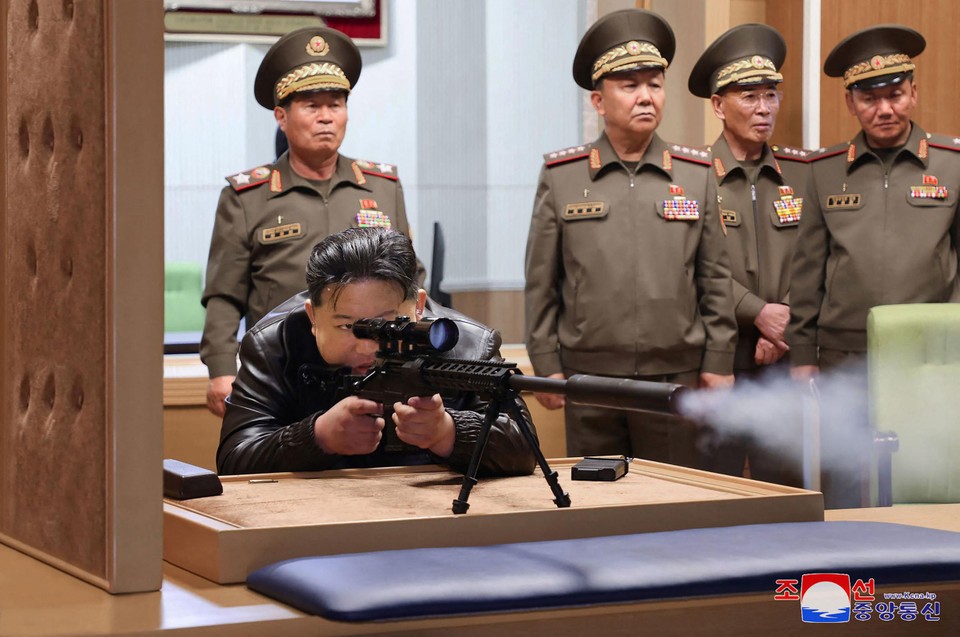 De Noord-Koreaanse leider test een scherpschuttersgeweer in een wapenfabriek.