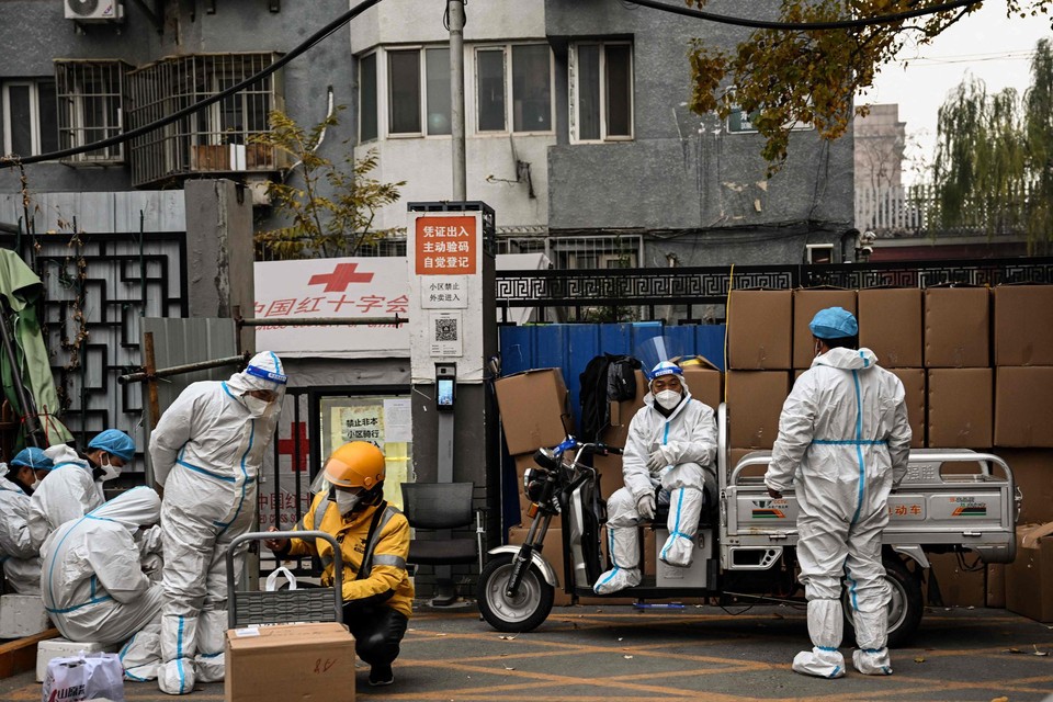Gezondheidswerkers bewaken de ingang van een woonwijk in Peking die in lockdown is geplaatst. 